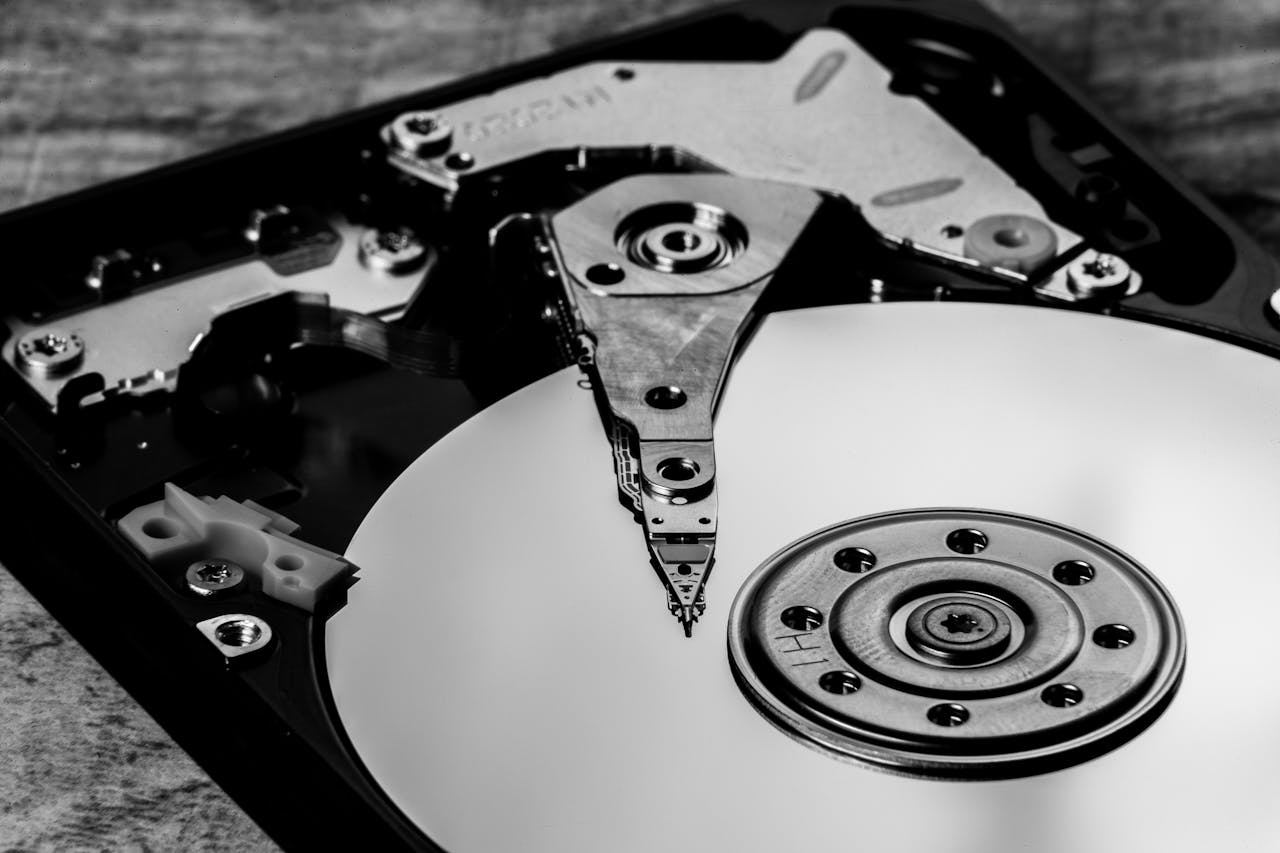 Detailed black and white image of an open hard drive, showcasing intricate components.